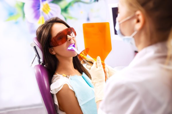 Overview of dental caries prevention. Woman at the dentist's chair during a dental procedure.. Healthy Smile.